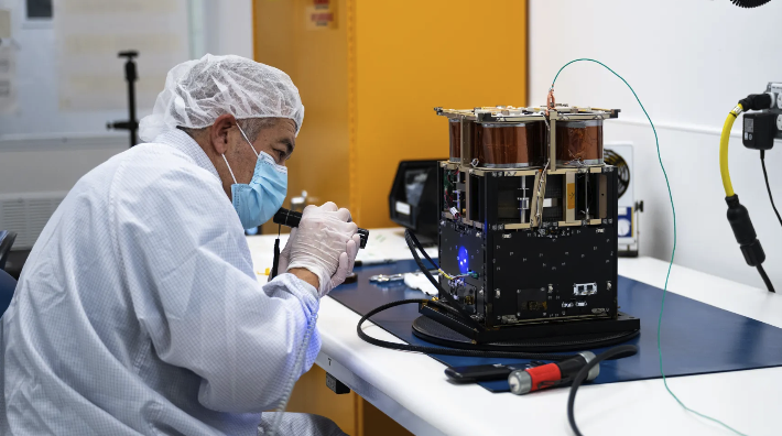 Mariano Perez, quality assurance engineer at NASA Ames, inspects the Advanced Composite Solar Sail System spacecraft. When the composite booms and solar sail deploy in orbit, they will measure about 860 square feet (80 square meters) – about the size of six parking spots. Credit: NASA/Brandon Torres NASA/Brandon Torres